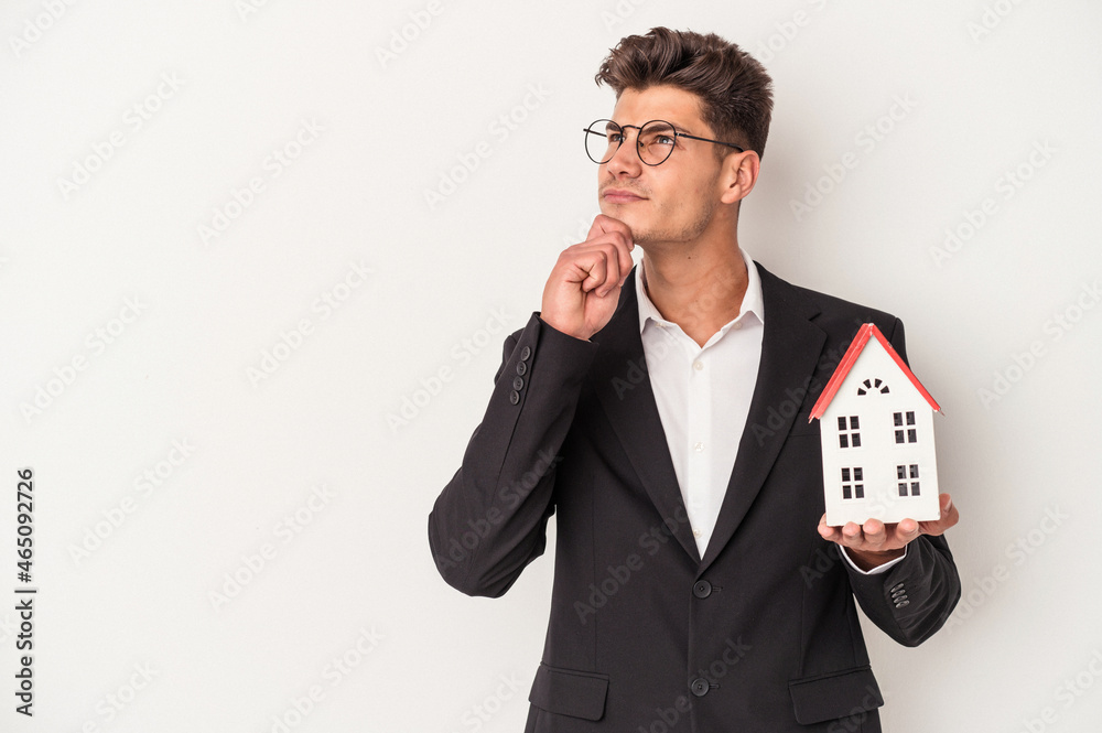 Young real estate caucasian agent isolated on white background looking sideways with doubtful and skeptical expression. Young real estate caucasian agent isolated on white background looking sideways with doubtful and skeptical expression.
