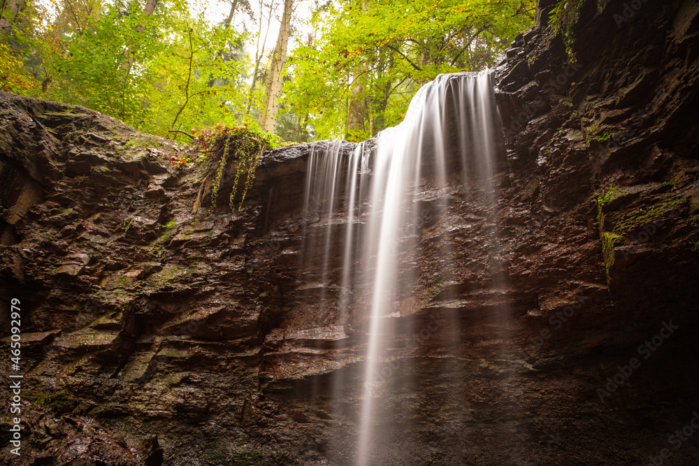 Obraz premium Waterfall cascade is flowing over a rock