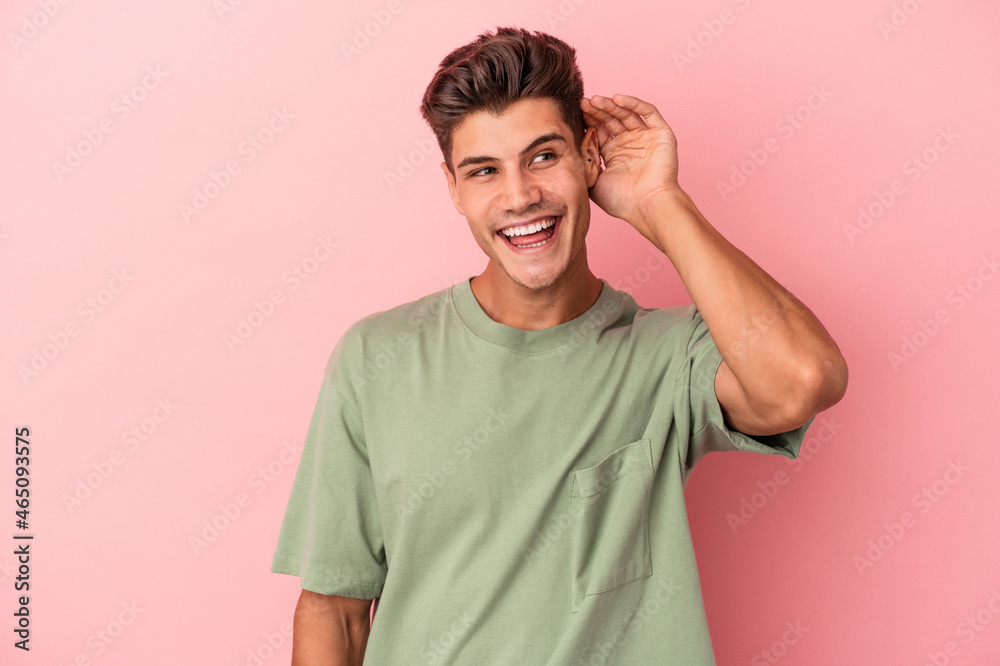 Young caucasian man isolated on pink background trying to listening a gossip. Young caucasian man isolated on pink background trying to listening a gossip.