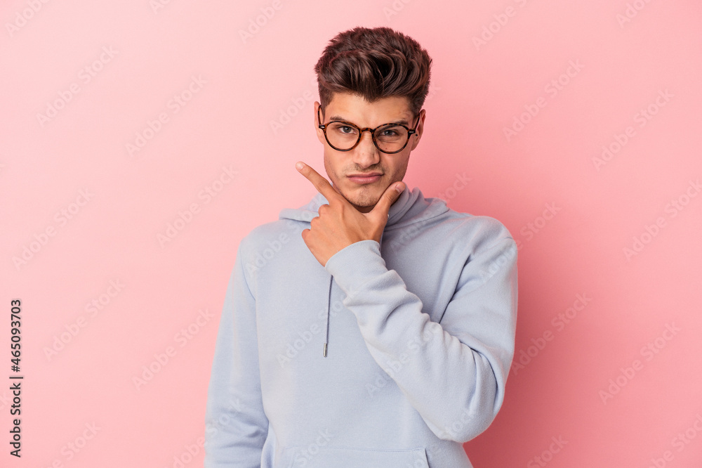 Young caucasian man isolated on pink background contemplating, planning a strategy, thinking about the way of a business.
