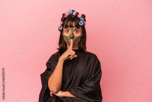 Young mixed race woman waiting in a Beaty salon isolated on pink background keeping a secret or asking for silence. © Asier