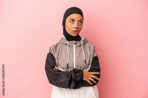 Young Arab woman with sport burqa isolated on pink background tired of a repetitive task.