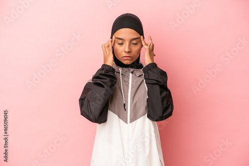 Young Arab woman with sport burqa isolated on pink background touching temples and having headache.