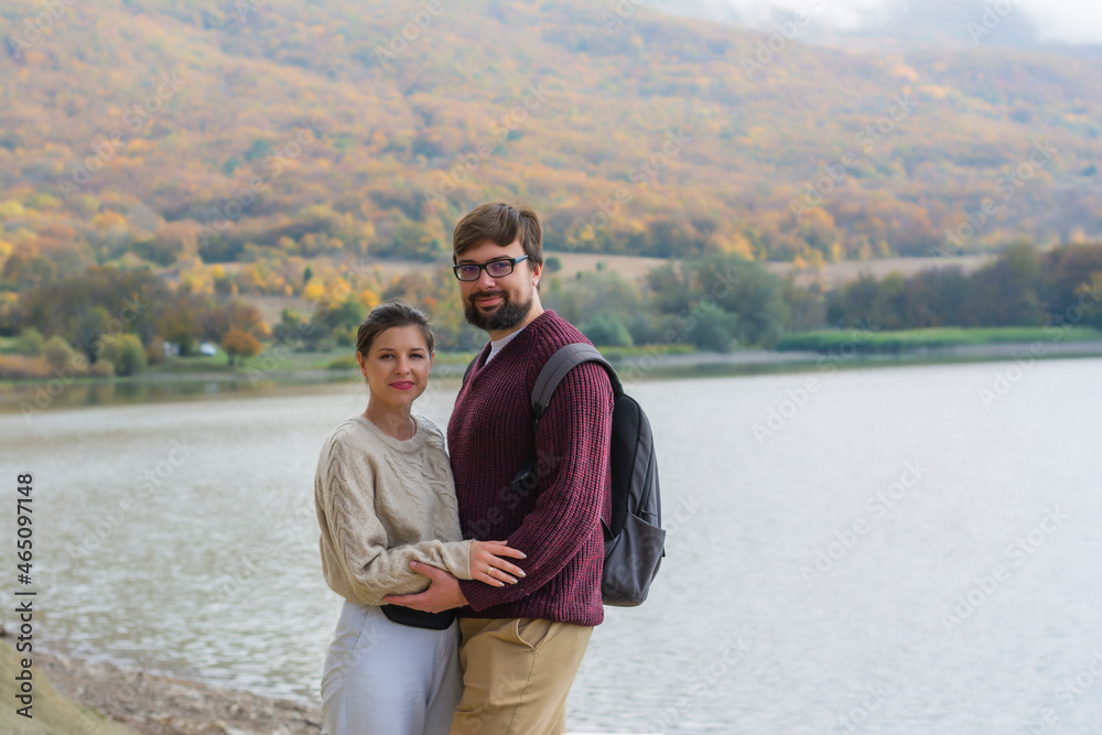 Family couple on vacation in the autumn in the forest near the lake in cozy knitted sweaters