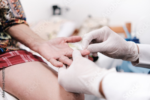 hands of doctor with gloves evaluating patient's hand