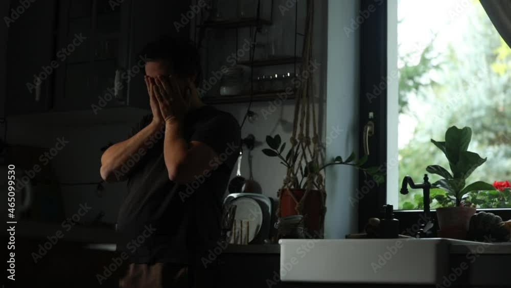 sad man stands next to window at kitchen sad man stands next to window at kitchen