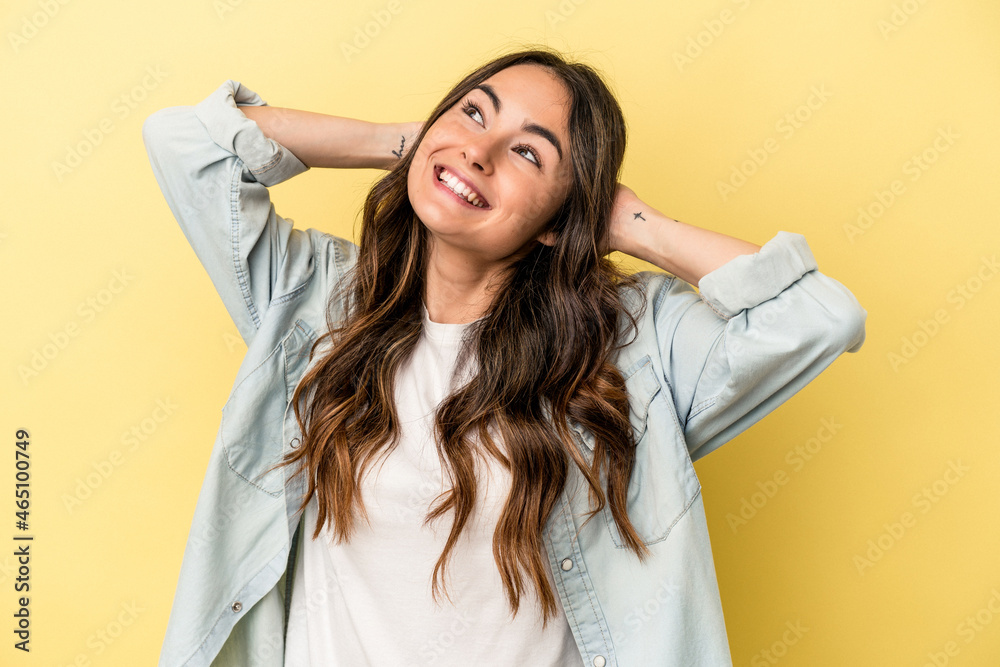 Naklejka premium Young caucasian woman isolated on yellow background feeling confident, with hands behind the head.