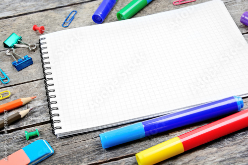 School supplies with empty notebook on wooden desk