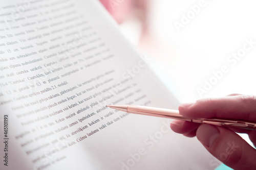 A person reading research paper with a pencil as a visual pacer to improve reading speed