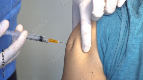 Nurse or medical staff in white gloves putting the vaccine with a needle in the arm to a boy for Covid-19 or coronavirus Sars Cov to avoid becoming seriously ill and the rise of the pandemic.