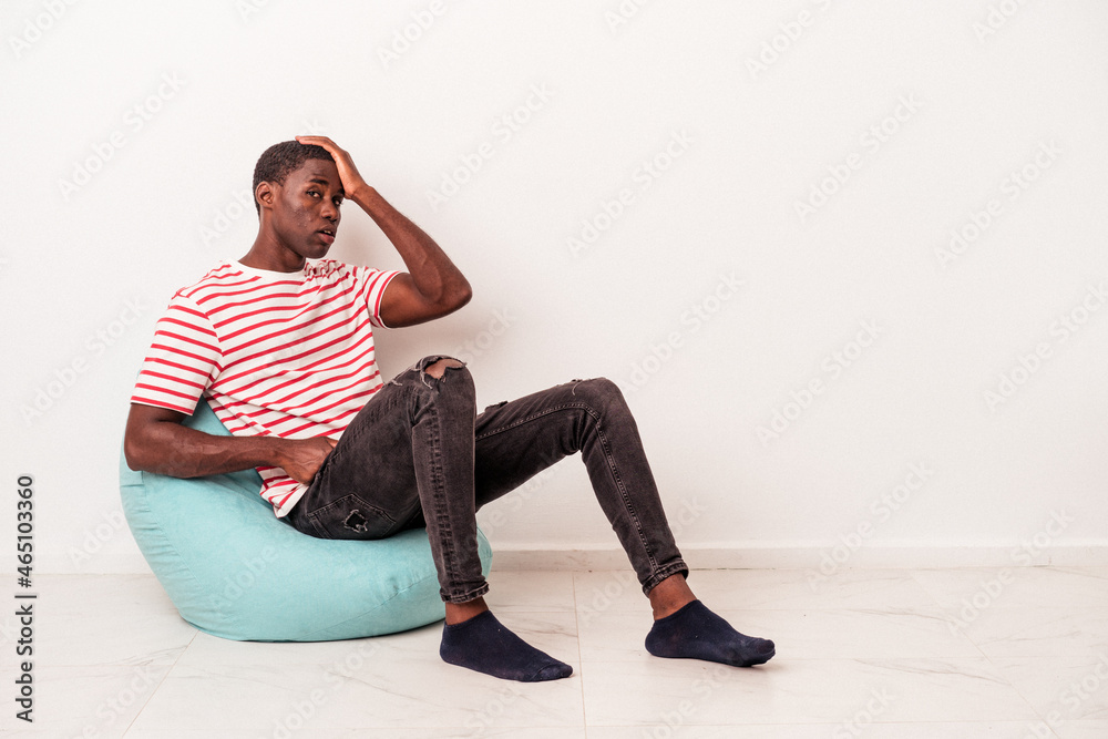 Young African American man sitting on a puff isolated on white background being shocked, she has remembered important meeting.