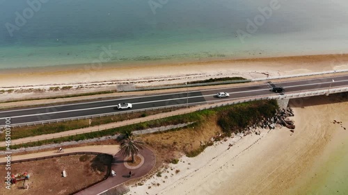 Aerial drone shot of the road linking the bay to an island. turquoise waters in the ocean and cars going through the bridge. beach
