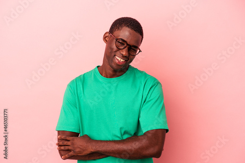 Young African American man isolated on pink background who feels confident, crossing arms with determination.