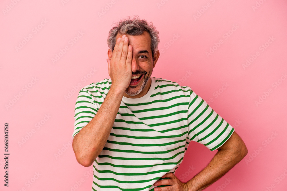 Middle age caucasian man isolated on pink background having fun covering half of face with palm. Middle age caucasian man isolated on pink background having fun covering half of face with palm.