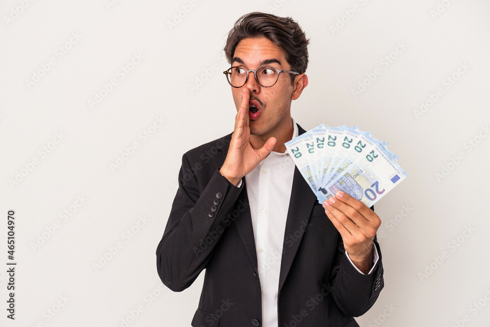 Young mixed race business man holding bills isolated on white background is saying a secret hot braking news and looking aside Young mixed race business man holding bills isolated on white background is saying a secret hot braking news and looking aside