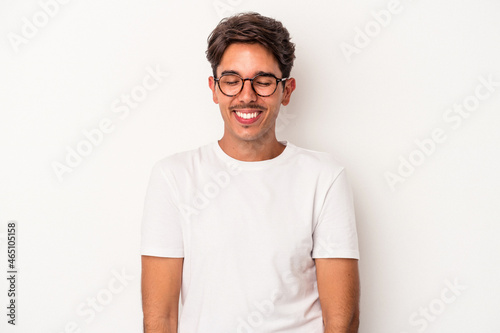 Young mixed race man isolated on white background laughs and closes eyes, feels relaxed and happy.