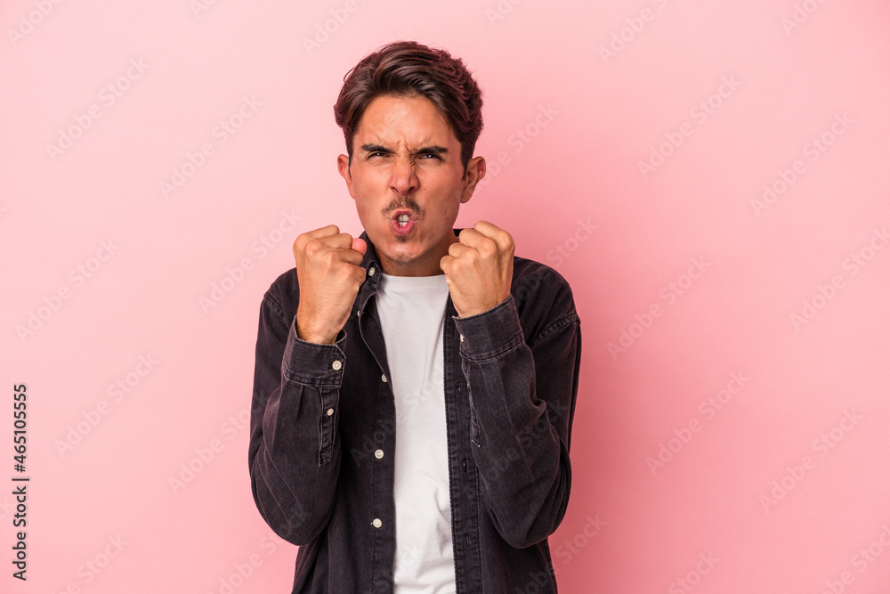Young mixed race man isolated on white background showing fist to camera, aggressive facial expression.