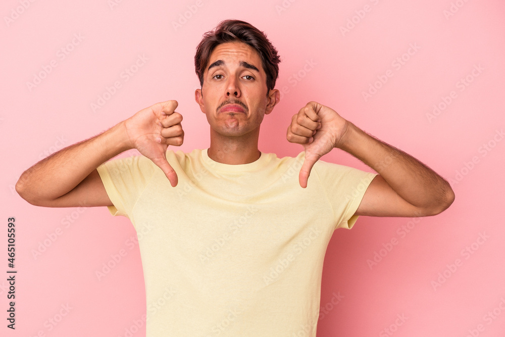 Young mixed race man isolated on white background showing a dislike gesture, thumbs down. Disagreement concept. Young mixed race man isolated on white background showing a dislike gesture, thumbs down. Disagreement concept.