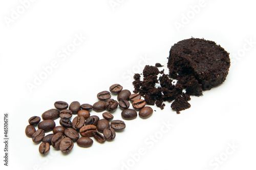The capsule of the used coffee grounds together with a small pile of roasted coffee beans demonstrating the process of  coffee grinding. 