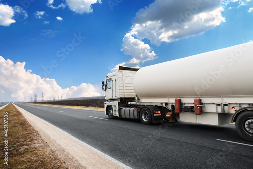 Tanker truck on a countryside road against a sky with clouds