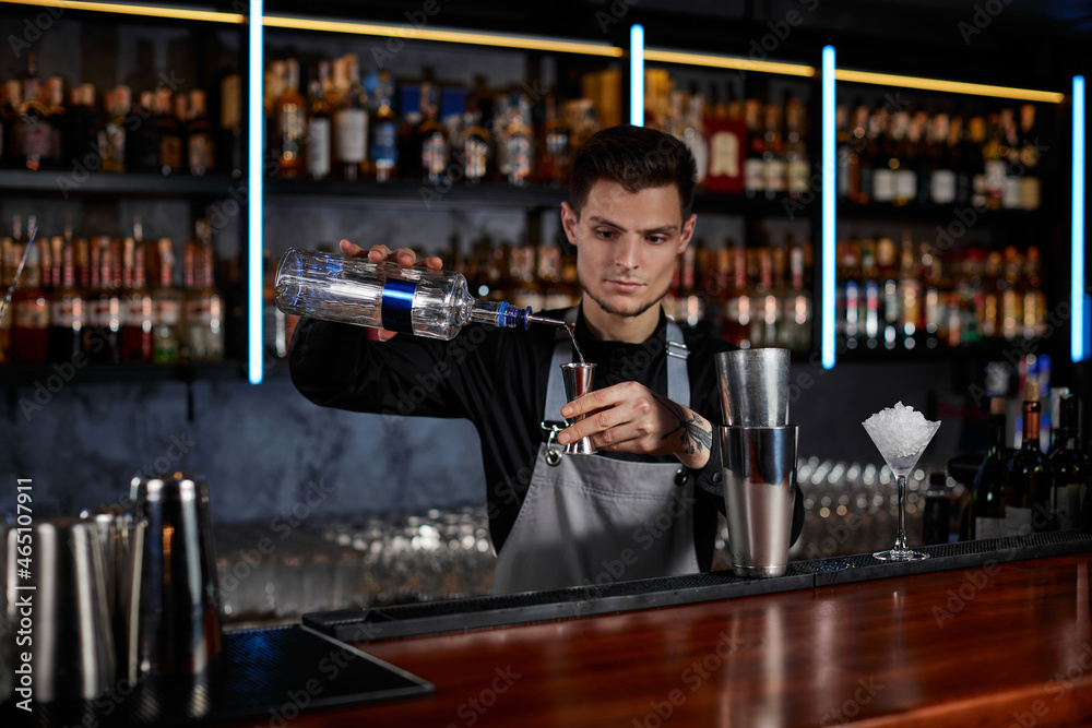 Bartender in apron adds ingredient to shaker Bartender in apron adds ingredient to shaker