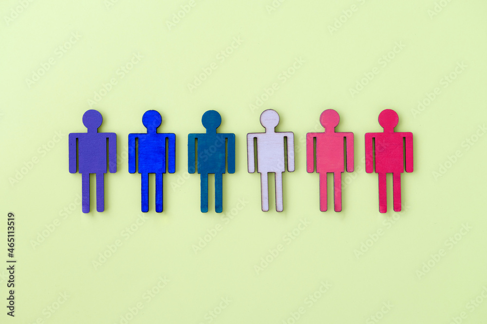 Multi-colored wooden figurines of man on yellow background Multi-colored wooden figurines of man on yellow background