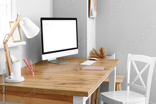 Modern workplace with blank computer screen near light wall © Pixel-Shot