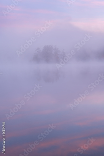 Foggy autumn landscape at dawn of an island on Hall Lake with mirrored reflections in calm water, Yankee Springs State Park, Michigan, USA