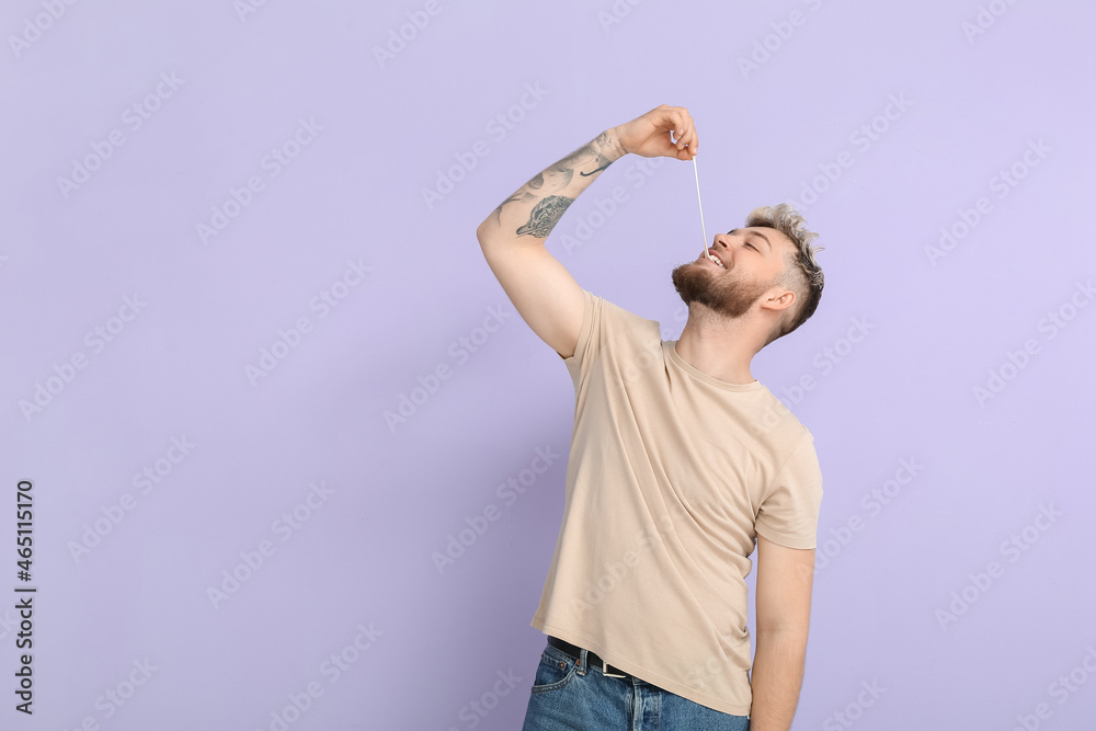 Young man with chewing gum on color background Young man with chewing gum on color background