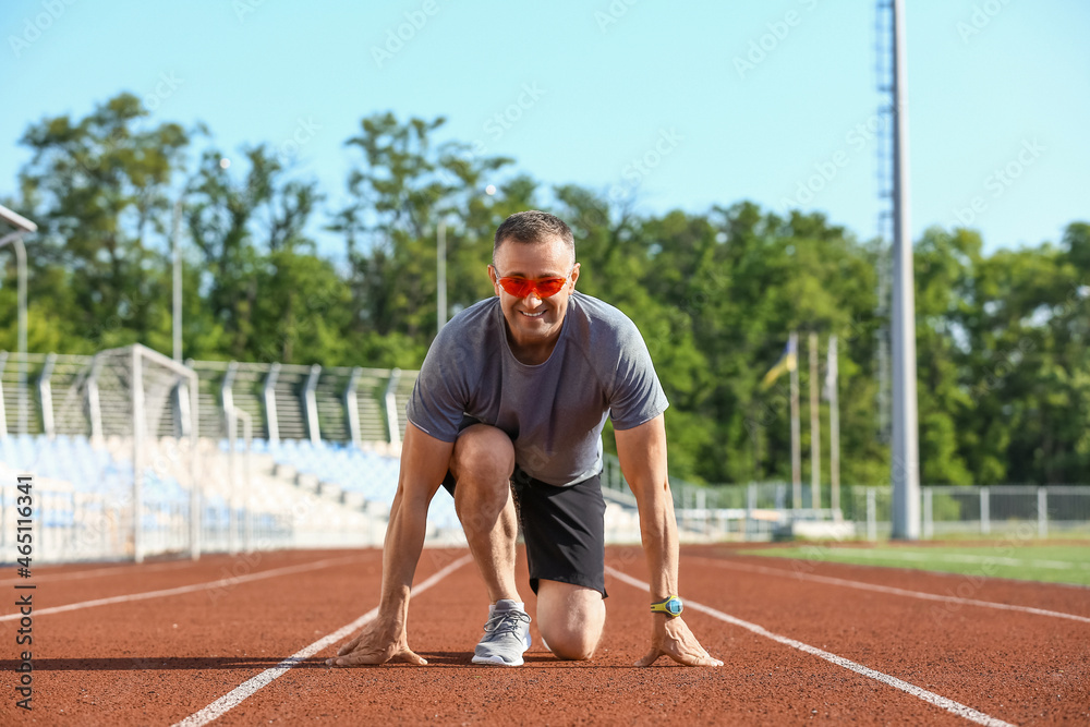 Sporty mature man getting ready to run at stadium Sporty mature man getting ready to run at stadium