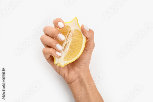 Female hand with beautiful manicure and sliced lemon on white background