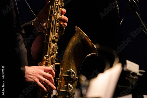 A tenor saxophone player playing a solo in front of a microphone during a live concert photo