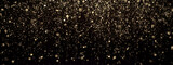 Gold glitter texture on black. Shinny small particles reflecting light.