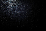 Shinny small particles glittering. Abstract texture on black background.