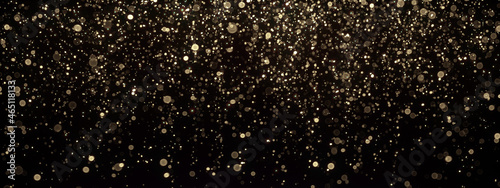 Gold glitter texture on black. Shinny small particles reflecting light.