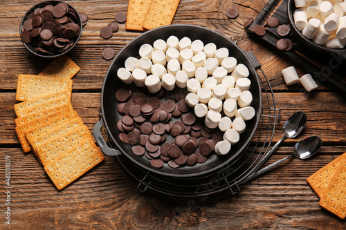 Frying pan with uncooked S'mores dip on wooden background