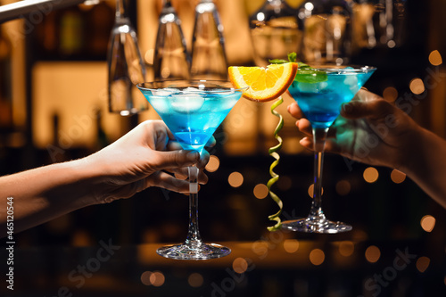 Women clinking glasses of Blue Lagoon cocktail in bar