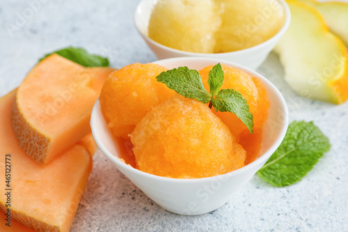 Bowls with tasty melon sorbet and mint on light background photo