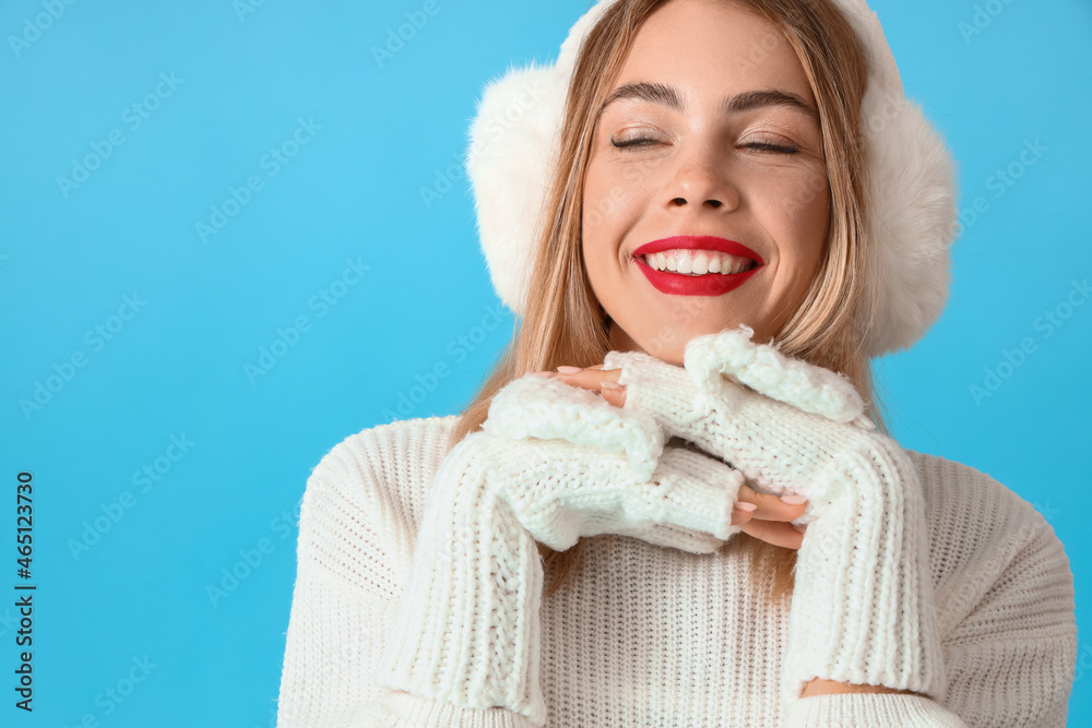 Beautiful young woman in earmuffs on blue background Beautiful young woman in earmuffs on blue background