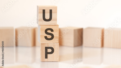 wooden cubes with letters USP arranged in a vertical pyramid, on the light background, reflection surface, concept