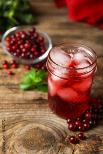 Glass with healthy cranberry juice on wooden background