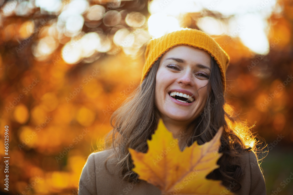 smiling modern woman in brown coat and yellow hat smiling modern woman in brown coat and yellow hat
