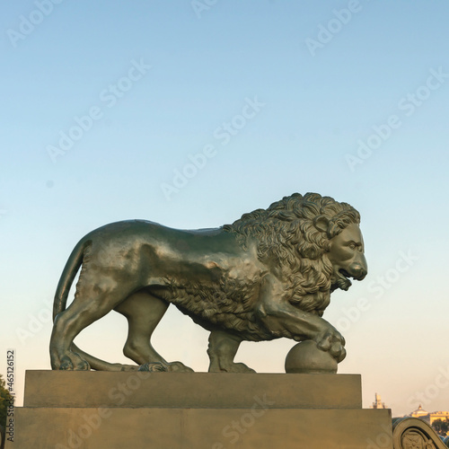 stone sculpture of a lion putting his paw on a ball on the embankment of the Neva River in St. Petersburg  Russia. The concept of strength  power.
