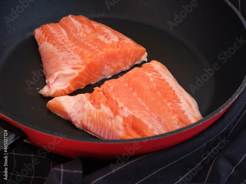 Two trout fillet slices lying in a frying pan ready to be cooked