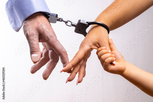 Male and female hands are handcuffed. The child's hand is holding on to the mother's finger, light background, selective focus, close-up. Concept: family ties of love, childhood affection, kinship.