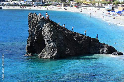 Scoglio sulla spiaggia di Monterosso al Mare con giovani che giocano photo