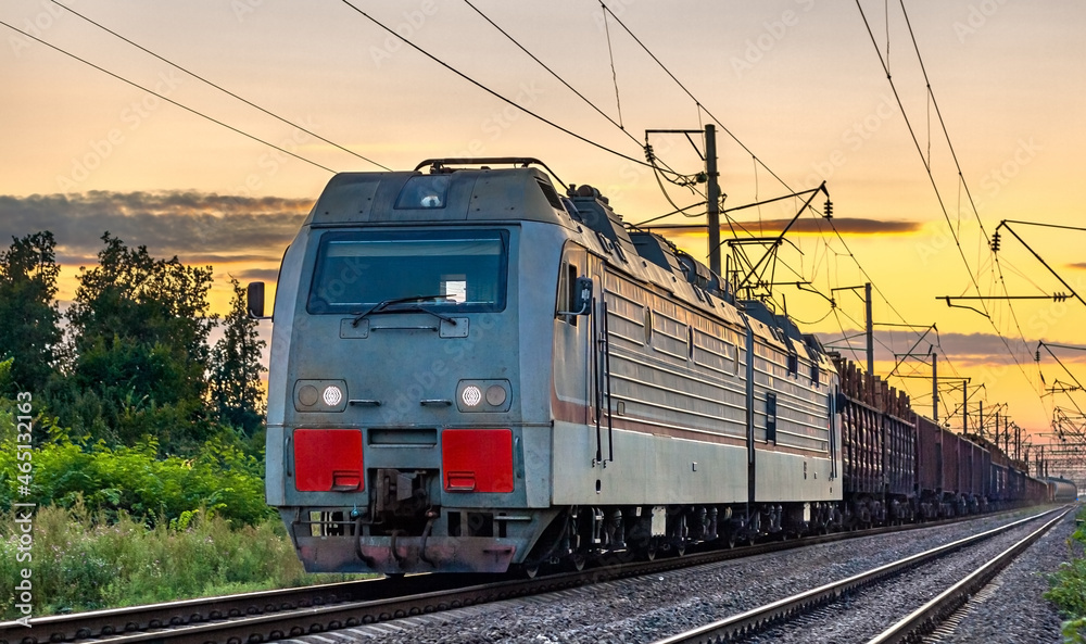 Electric locomotive hauling a cargo train at sunset