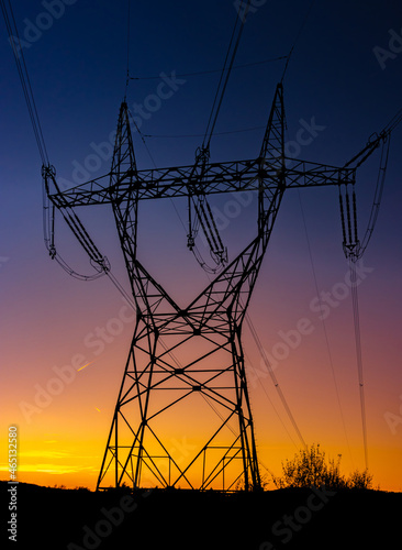 Silhouette of a high voltage tower with the sunset on a background