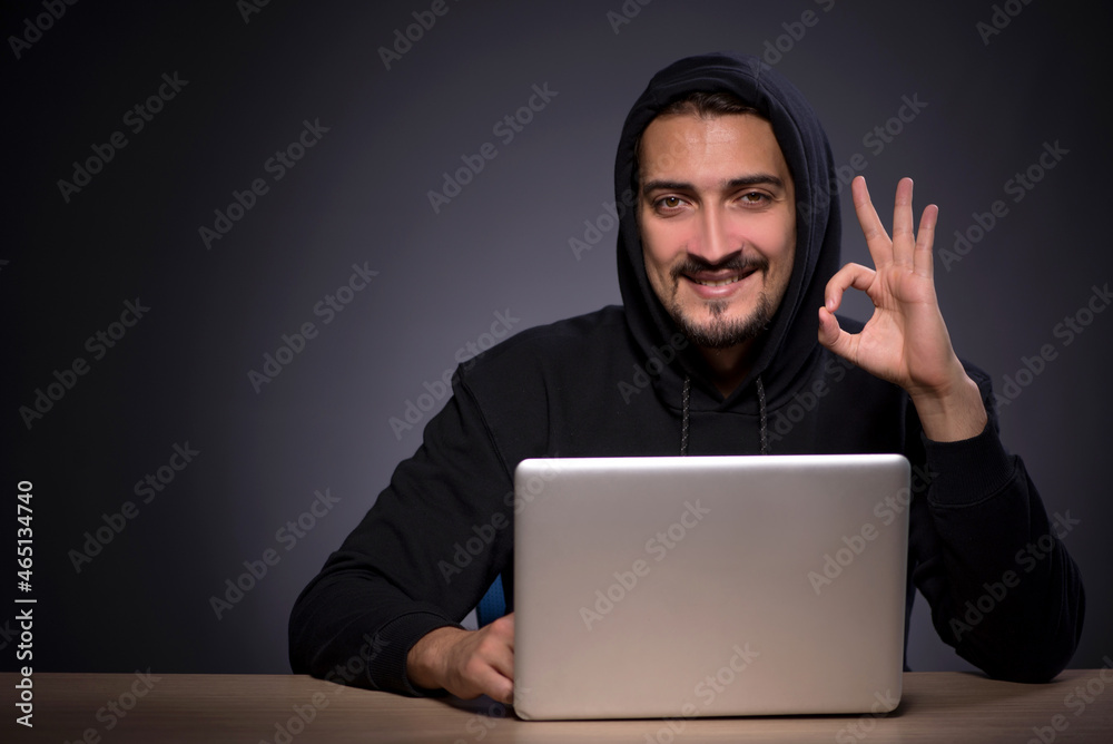 Young male hacker on grey background Young male hacker on grey background