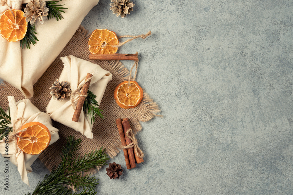 Fototapeta premium Zero waste christmas concept. Packed in natural fabric gifts and decorations from natural materials on gray table, top view, copy space